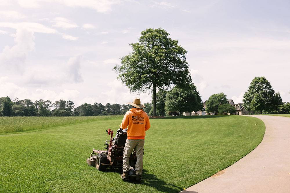 Lawn care worker mowing a large grassy area in Metro Atlanta